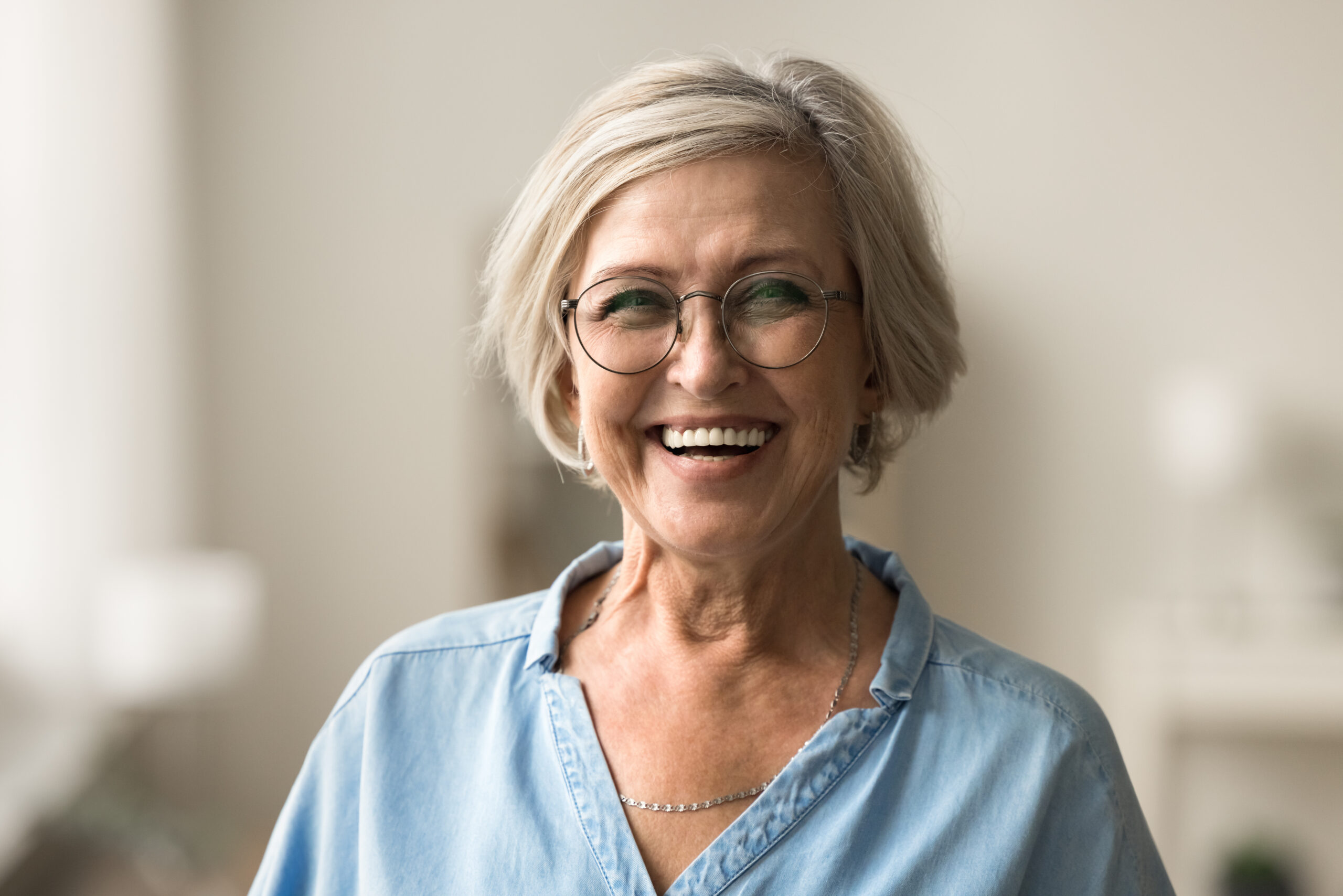 Cheerful pretty elder woman in elegant glasses looking at camera